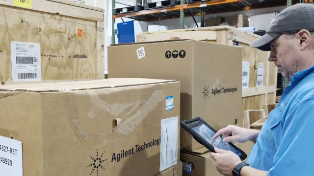 An AMP Tech team member checking a tablet beside boxed, labelled instruments