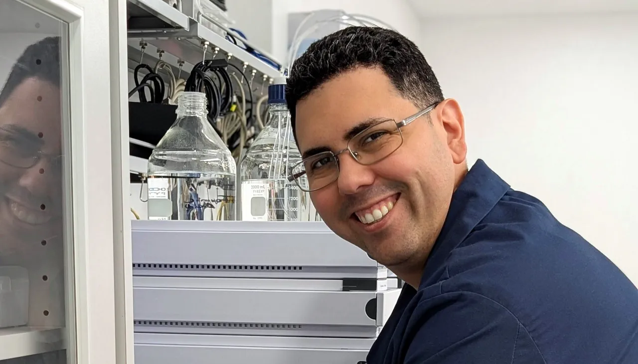 Smiling AMP Tech technician at an HPLC system in the Longwood, Florida lab