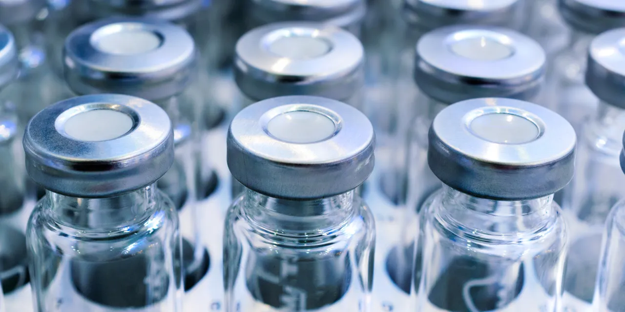 Rows of clear laboratory vials with crimp caps under cool blue light